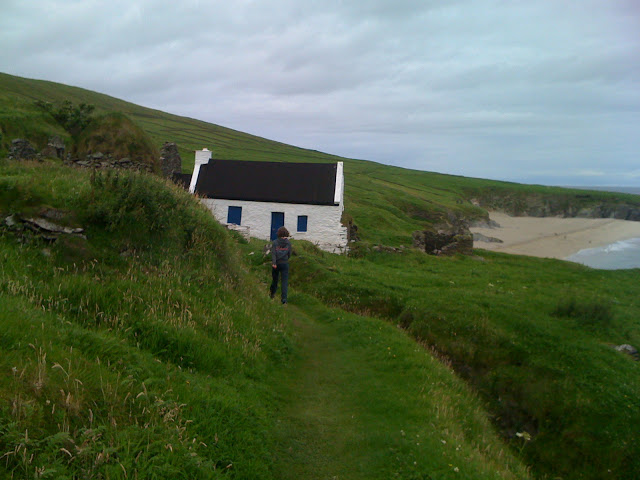 Cottage on green hillside in Ireland.