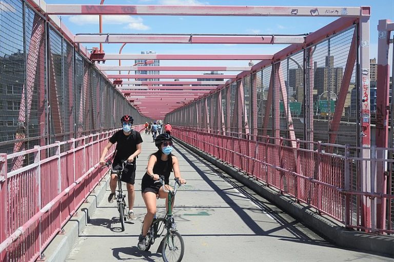Looking east at bikers on Williamsburg Bridge on a sunny midday 13 June 2020