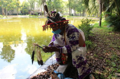 The mara’akame, wearing a face mask, checks his messages before doing a water blessing in Parque Agua Azul, Guadalajara, in August 2020 (T. Barnett)