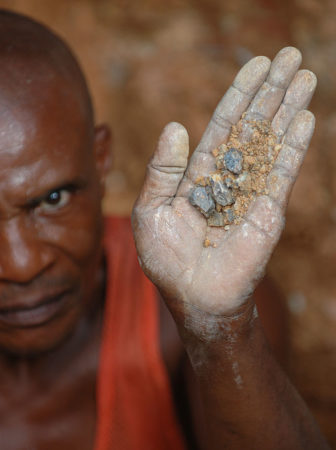 Wolframite and Casserite in the hands of a miner in the Democratic Republic of the Congo.
