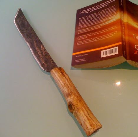 The knife I created on the forge, with a book for size reference. It used to be an old car part.