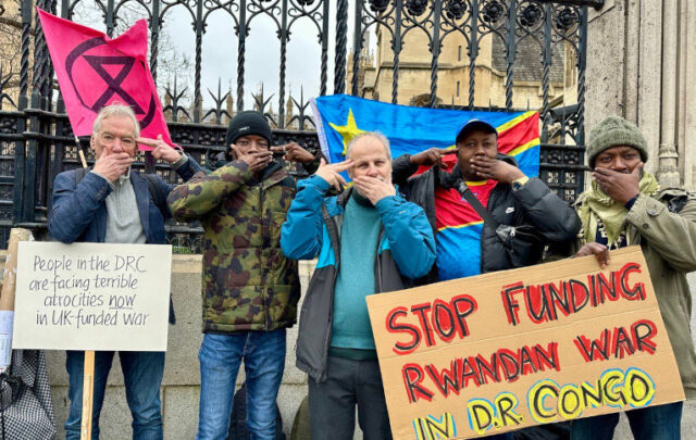 XR activists outside the UK Parliament protest the financing of violence in the DRC. The hand gesture, used by Congolese protesters to call out inaction of international and regional powers, represents being silenced with a gun to your head.